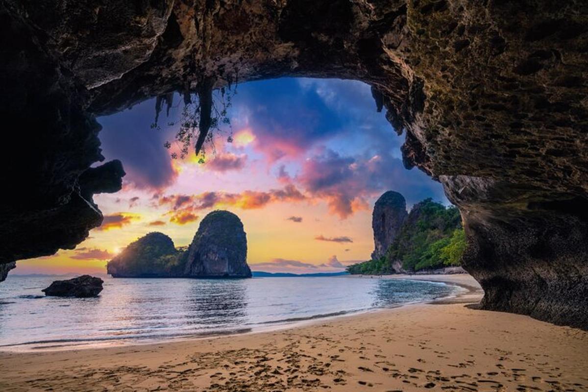 una grotta su una spiaggia con un tramonto sullo sfondo