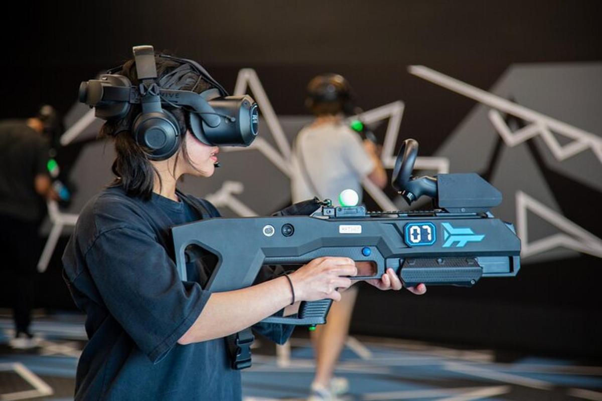 žena s brýlemi pro virtuální realitu a zbraní v ruce