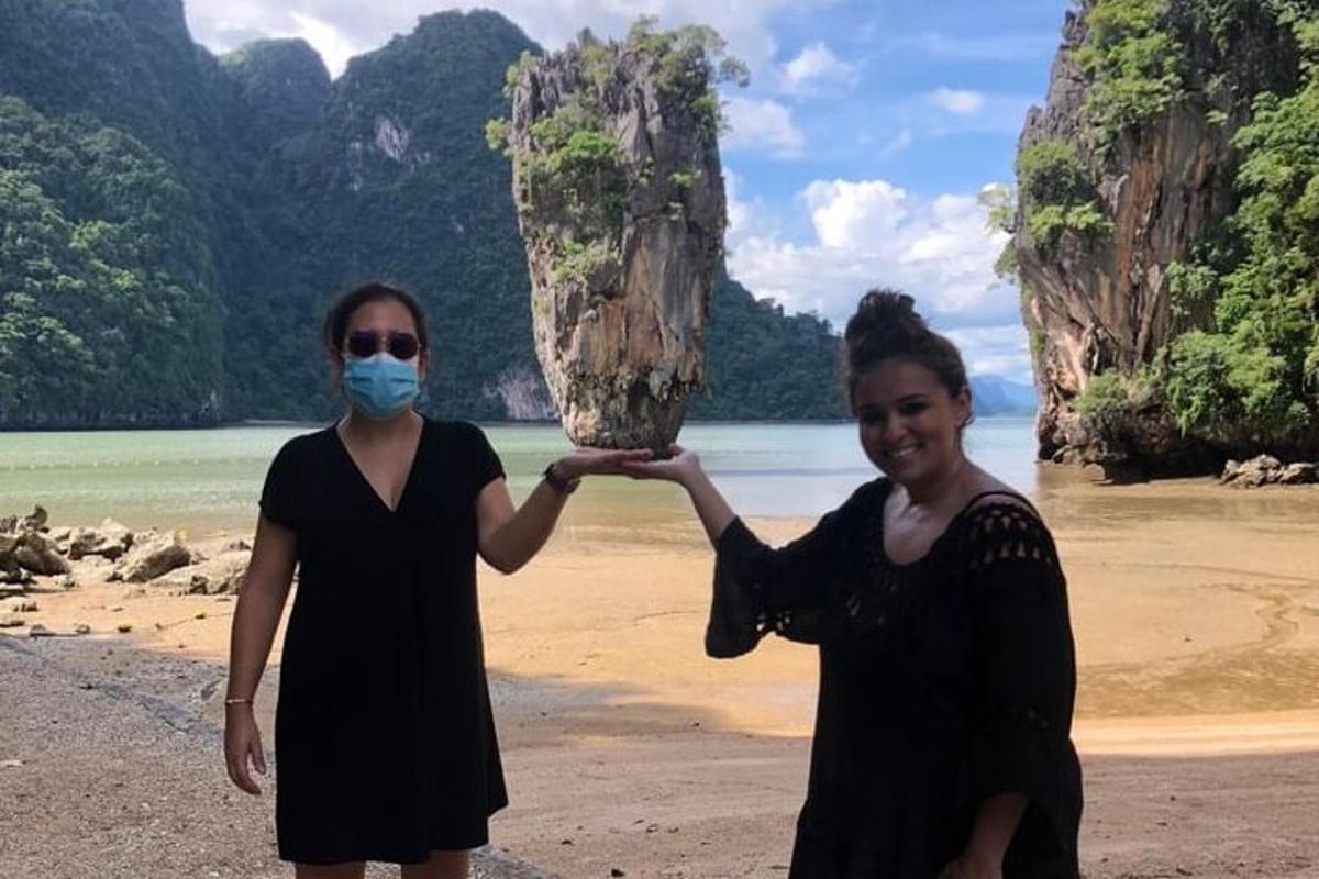dua wanita berdiri di pantai dengan topeng di muka mereka