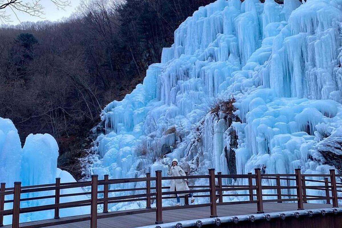 Un hombre está parado junto a una cascada congelada.
