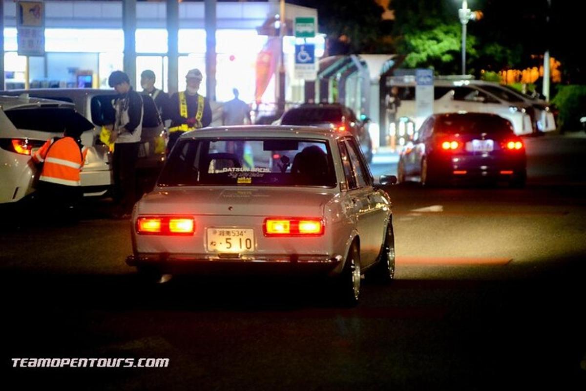a small car driving down a street at night