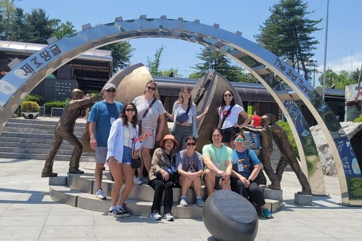 un gruppo di persone in posa davanti a una scultura