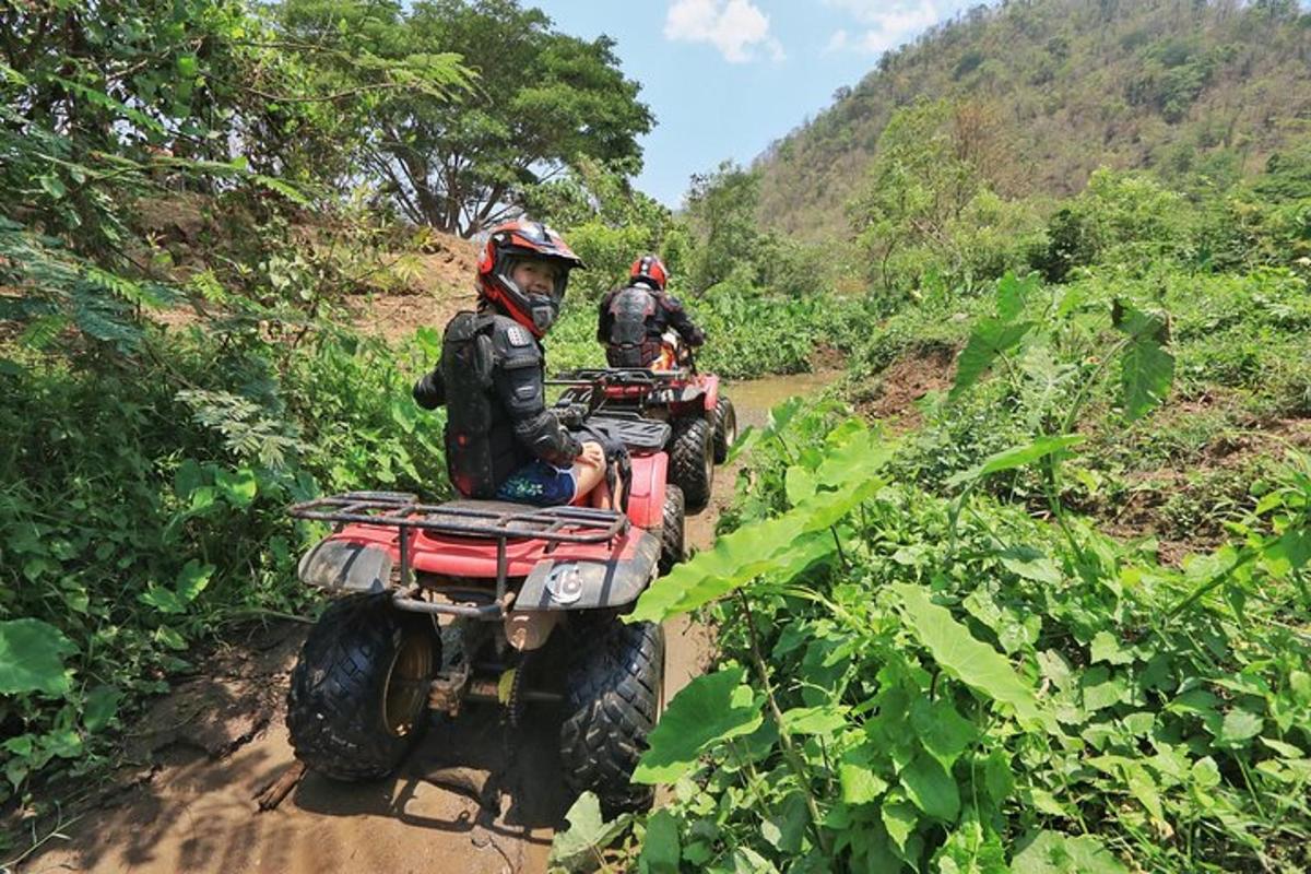 duas pessoas andando de quadriciclo em uma trilha de terra