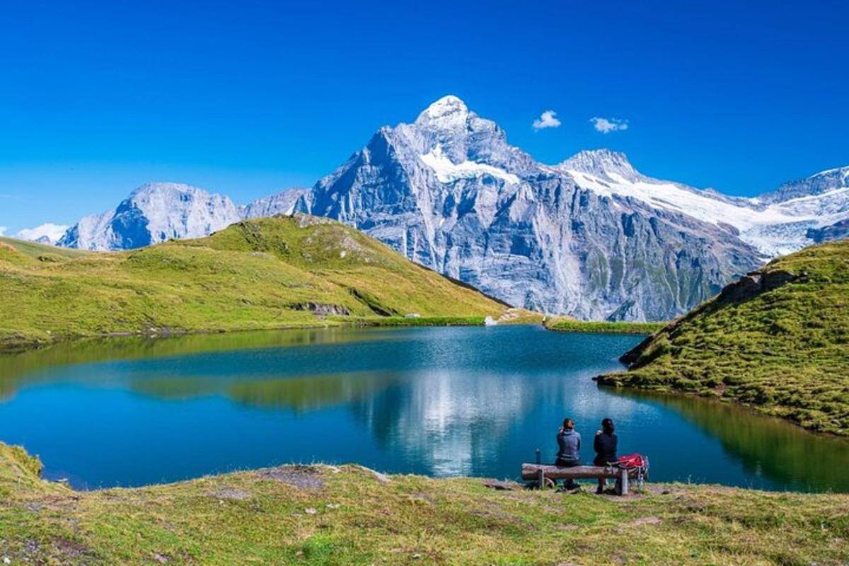 dua orang duduk di meja piknik di depan danau