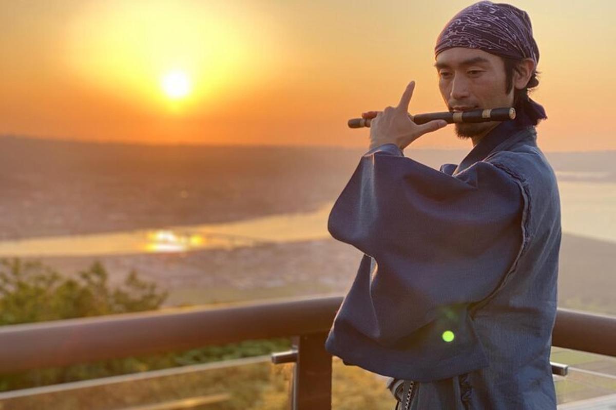a man playing a violin with the sunset in the background