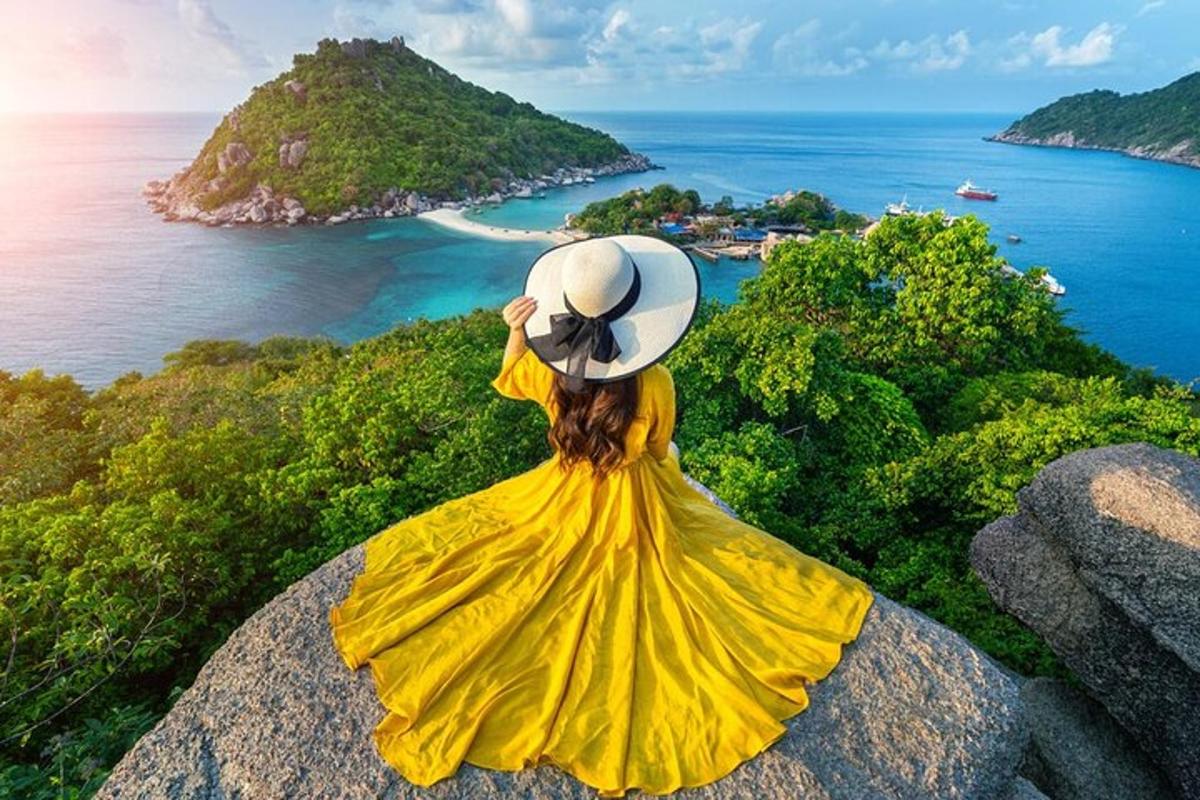 uma mulher de vestido amarelo sentada em uma rocha olhando para o oceano