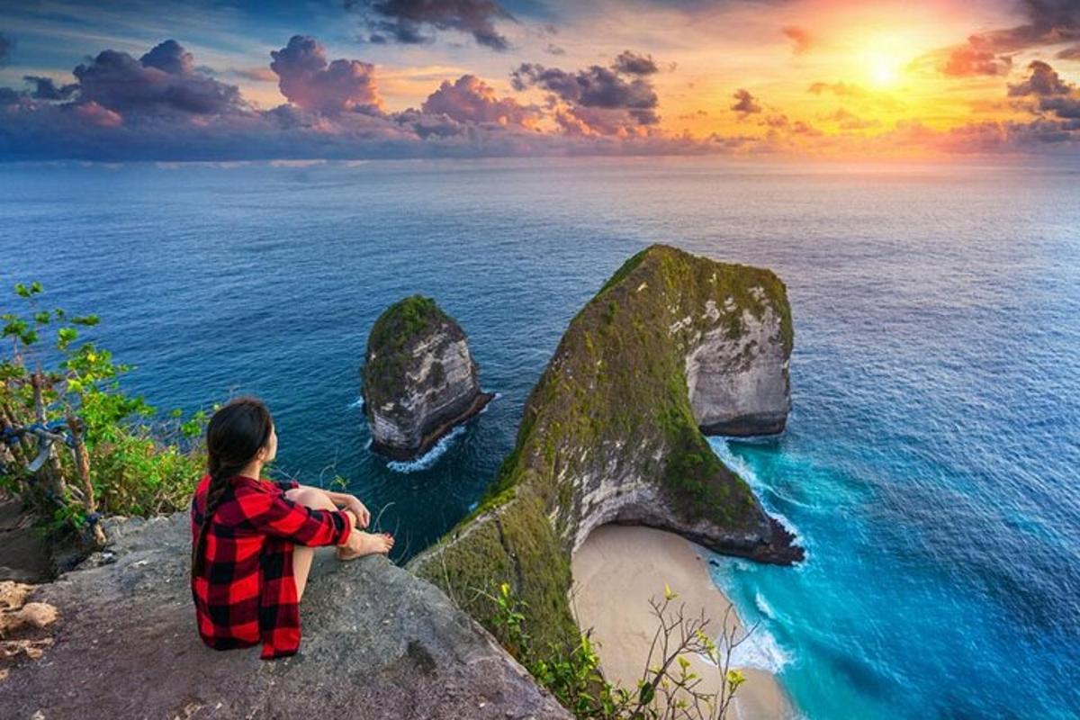seseorang yang duduk di atas batu yang menghadap ke lautan