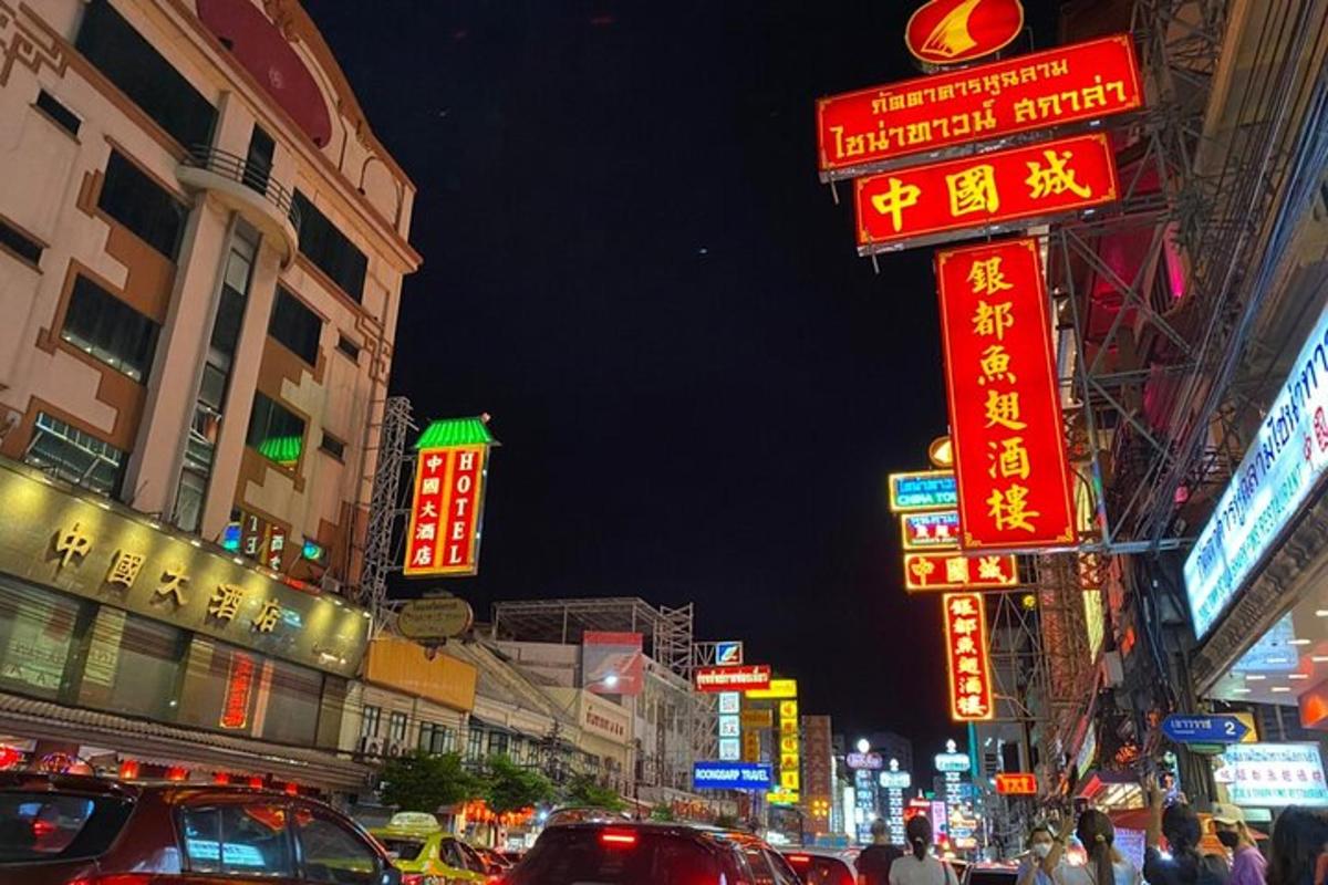una strada cittadina trafficata con insegne al neon di notte
