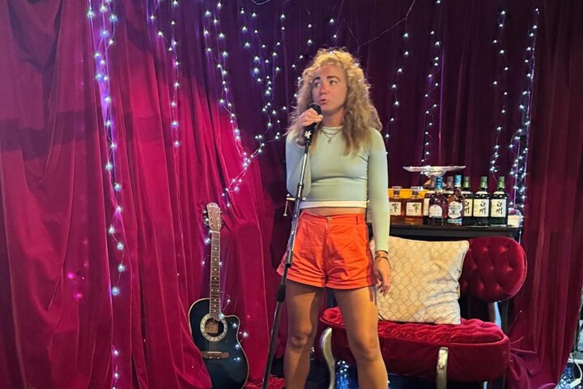 a woman singing into a microphone in front of a guitar