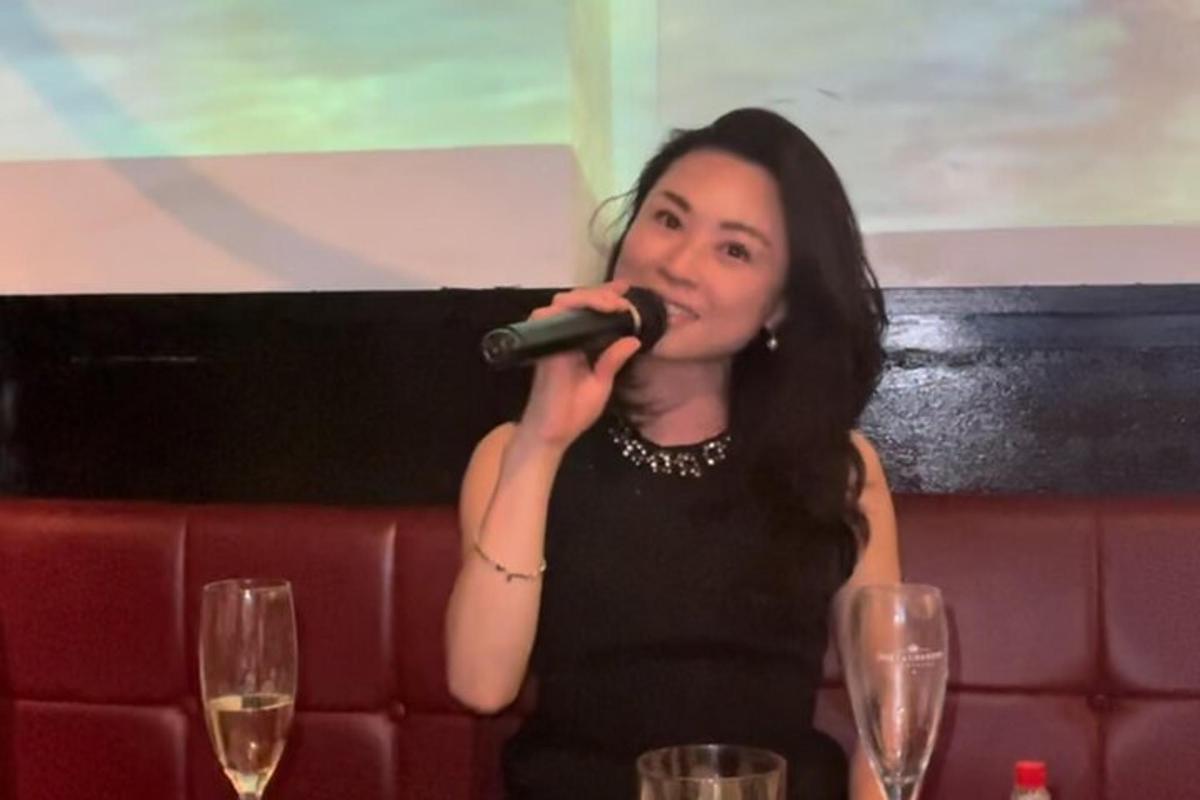a woman in a black dress singing into a microphone