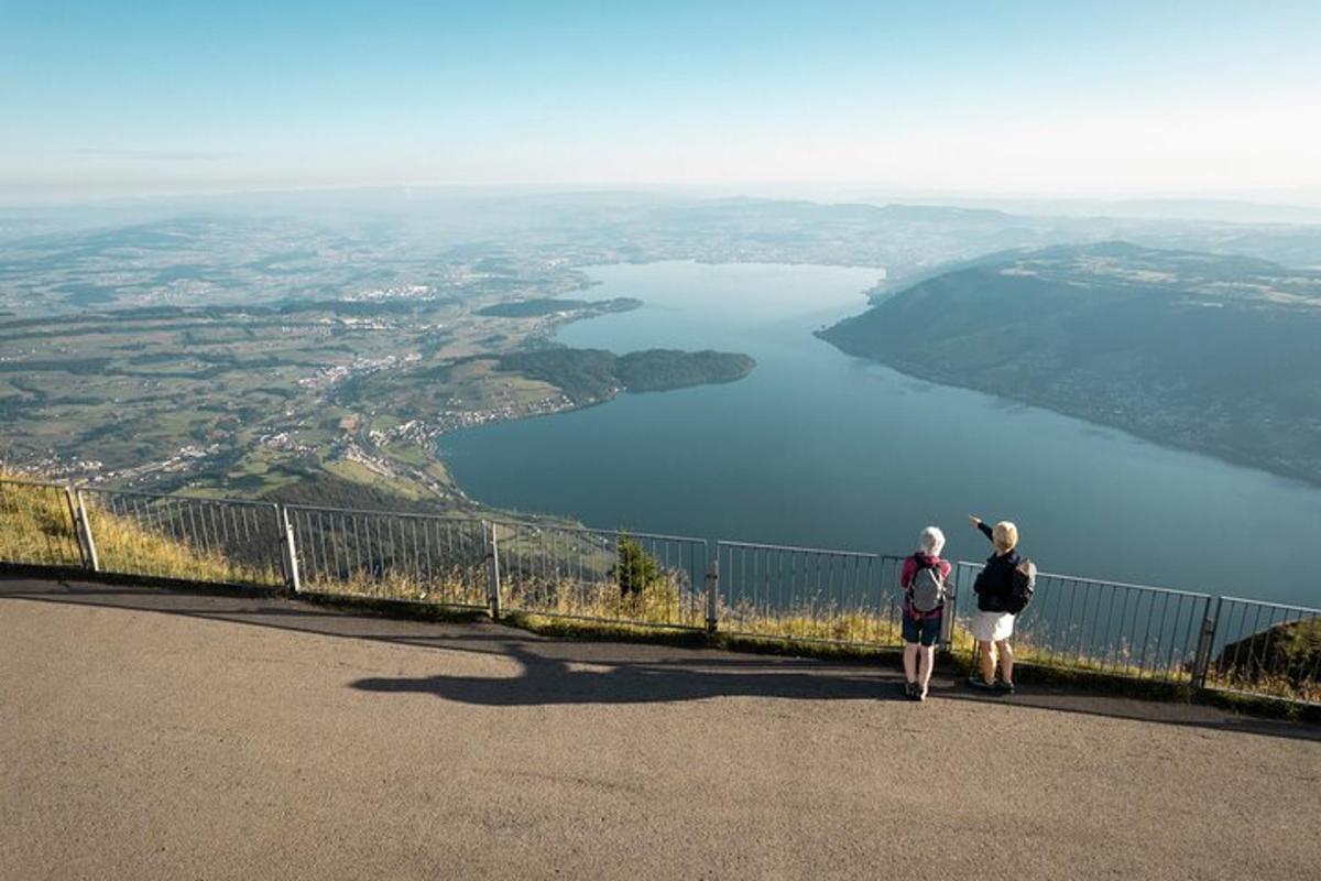 duas pessoas em pé em uma colina olhando para um lago