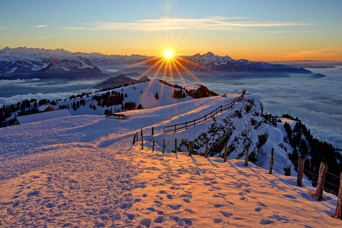 uma montanha coberta de neve com o sol no horizonte