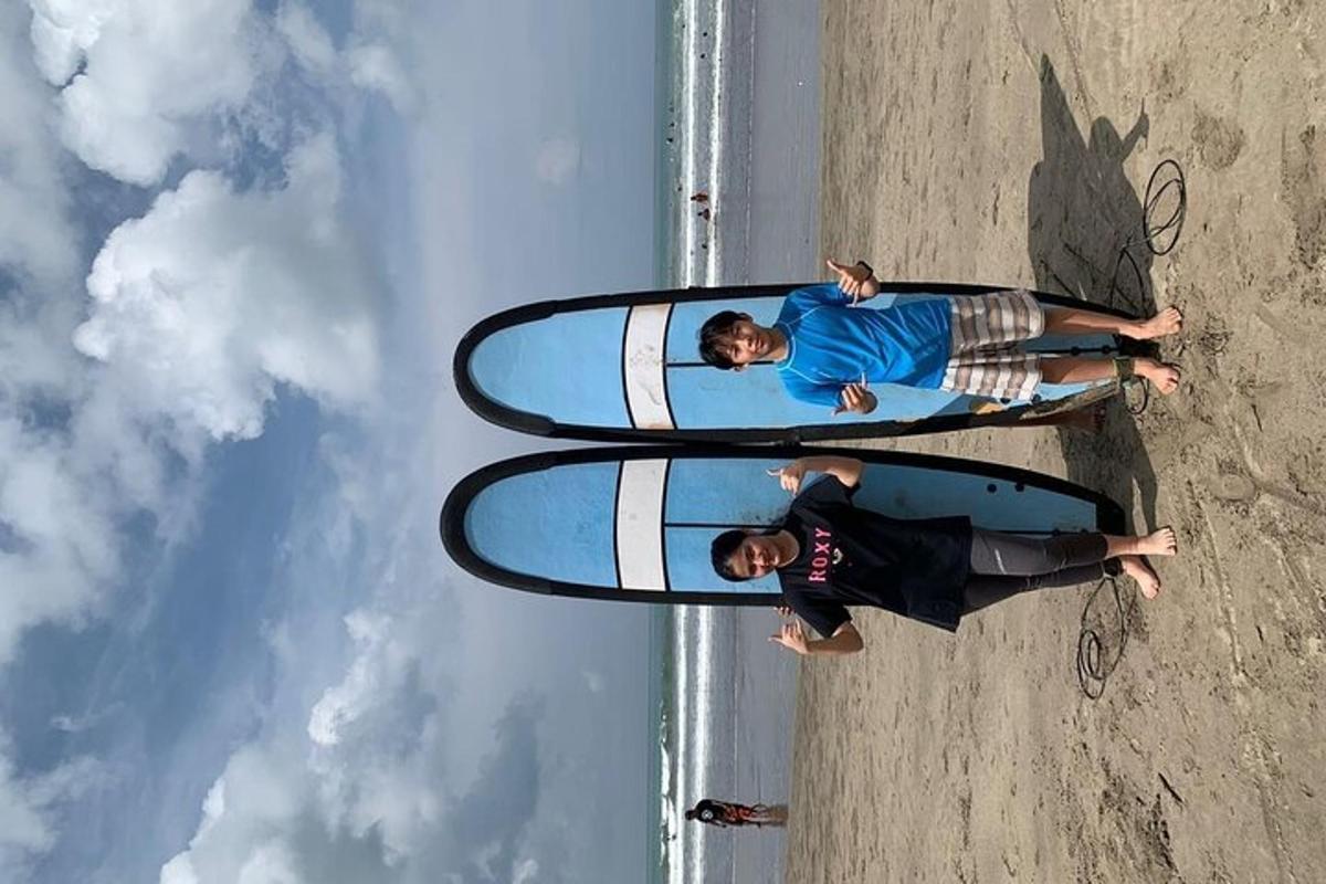Dva človeka stojita z deskami za surfanje na plaži