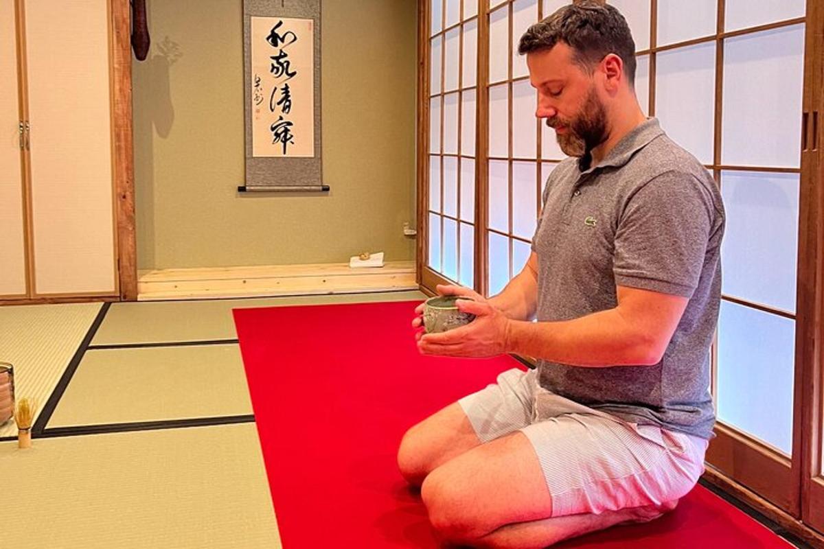 一位男士坐在红地毯上，手里拿着一个杯子
