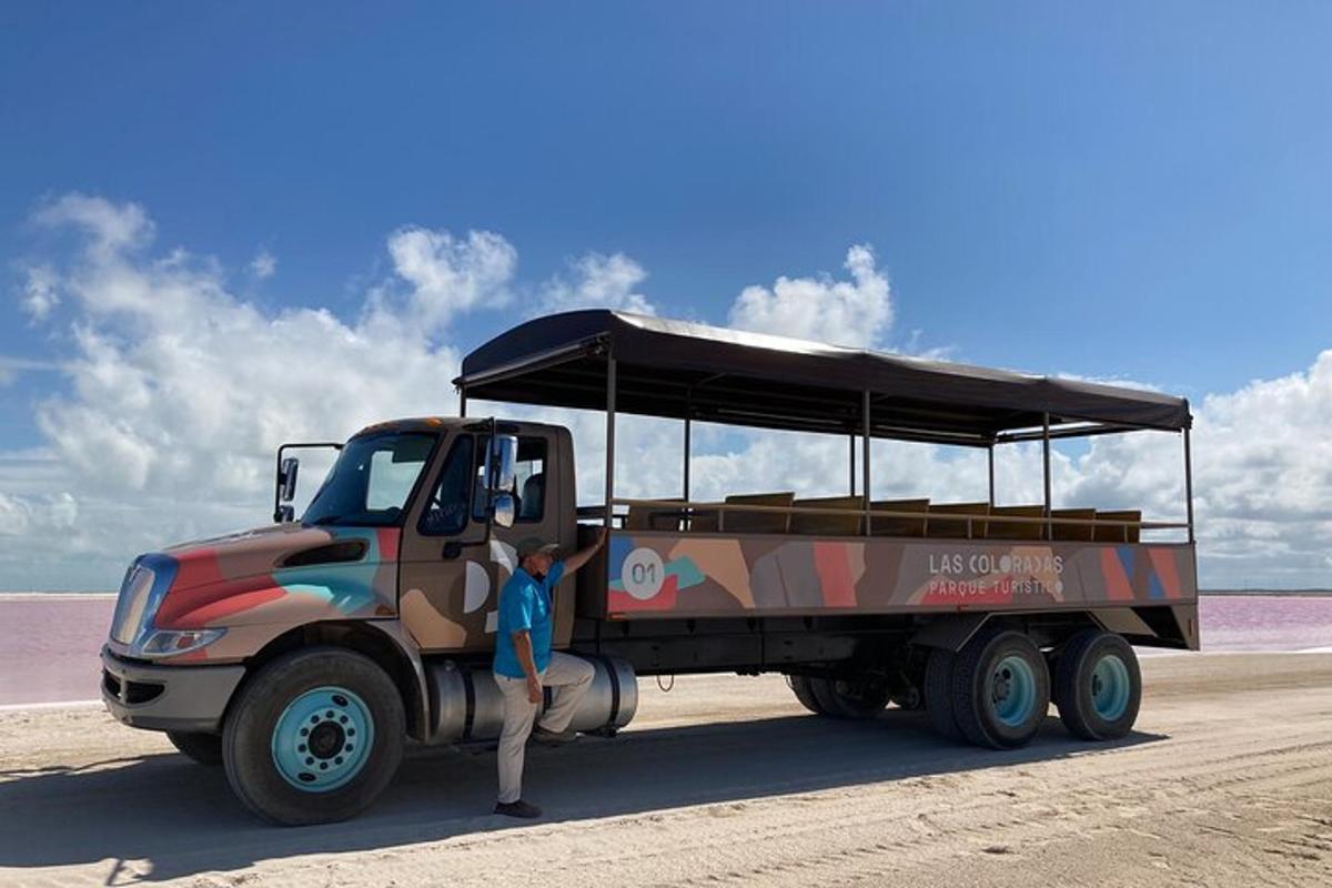Una persona parada junto a un camión camuflado en la playa.