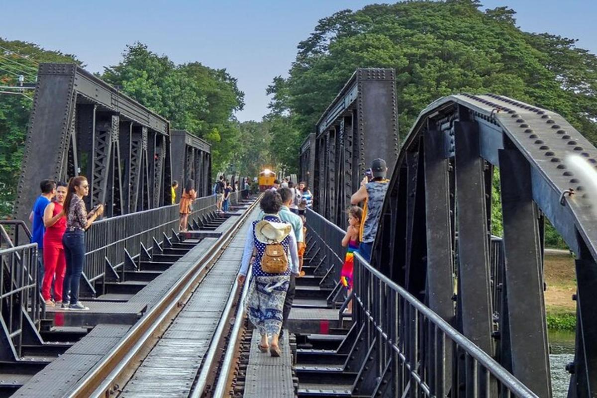 a group of people waiting for a train on a bridge