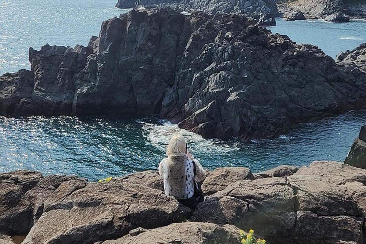 a person sitting on a rock looking at the ocean