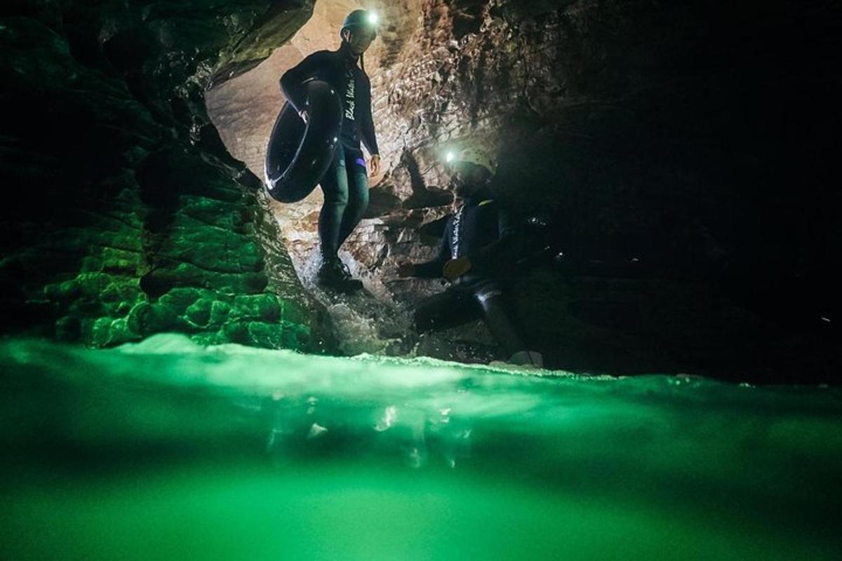 a man is walking through a cave with a surfboard