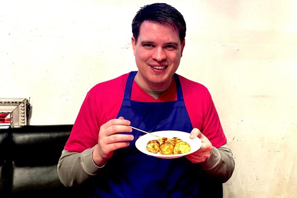 a man in a blue apron holding a plate of food
