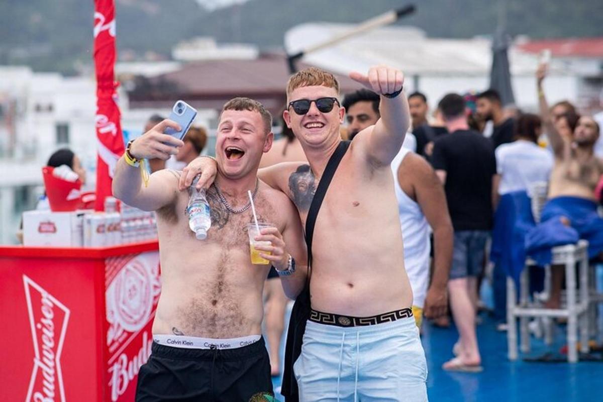 two shirtless men standing in a crowd at a festival