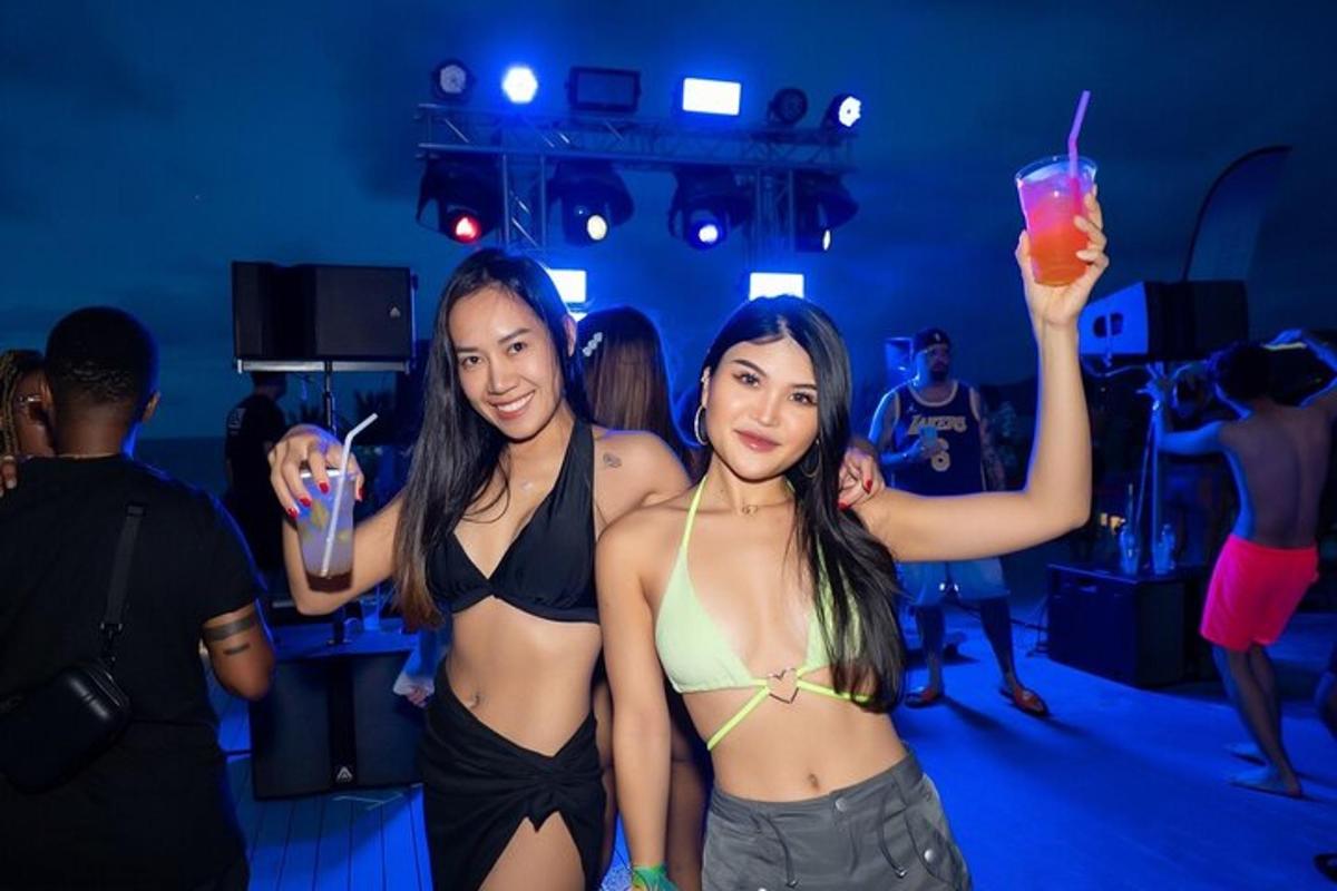 two women in bikinis holding a drink in a club