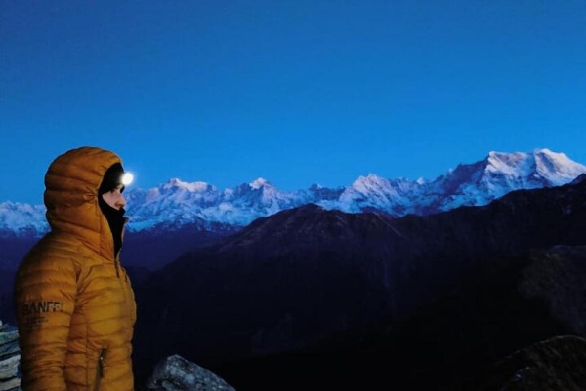 a person in a yellow jacket standing on a mountain