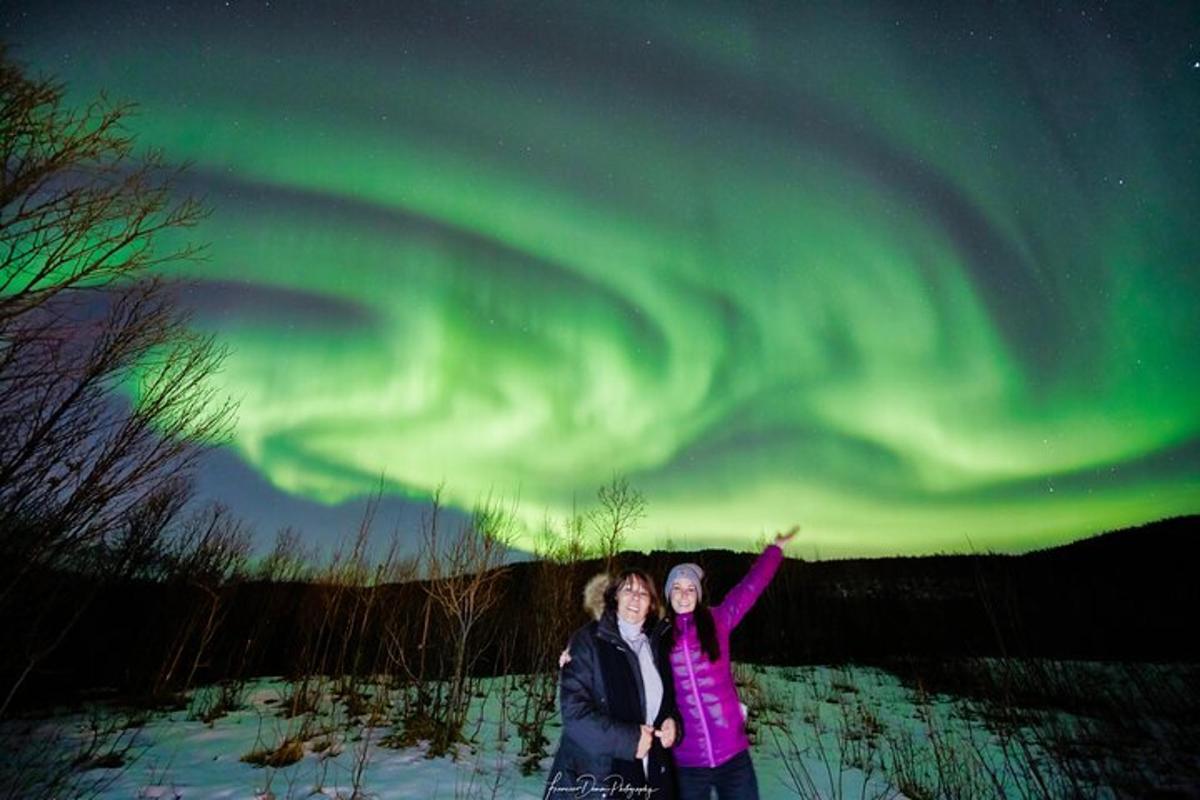 Dve ženski stojita pod auroro borealis