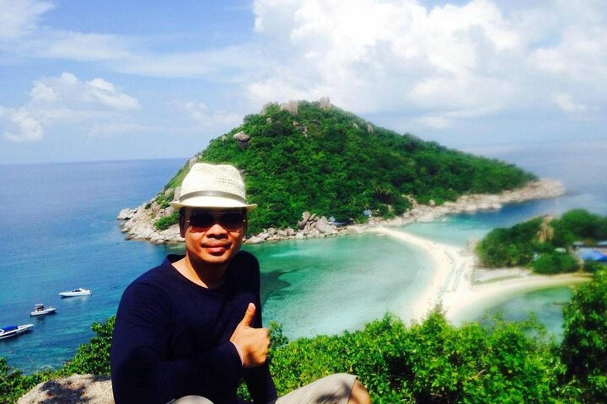 seorang pria mengacungkan jempol di depan sebuah pulau