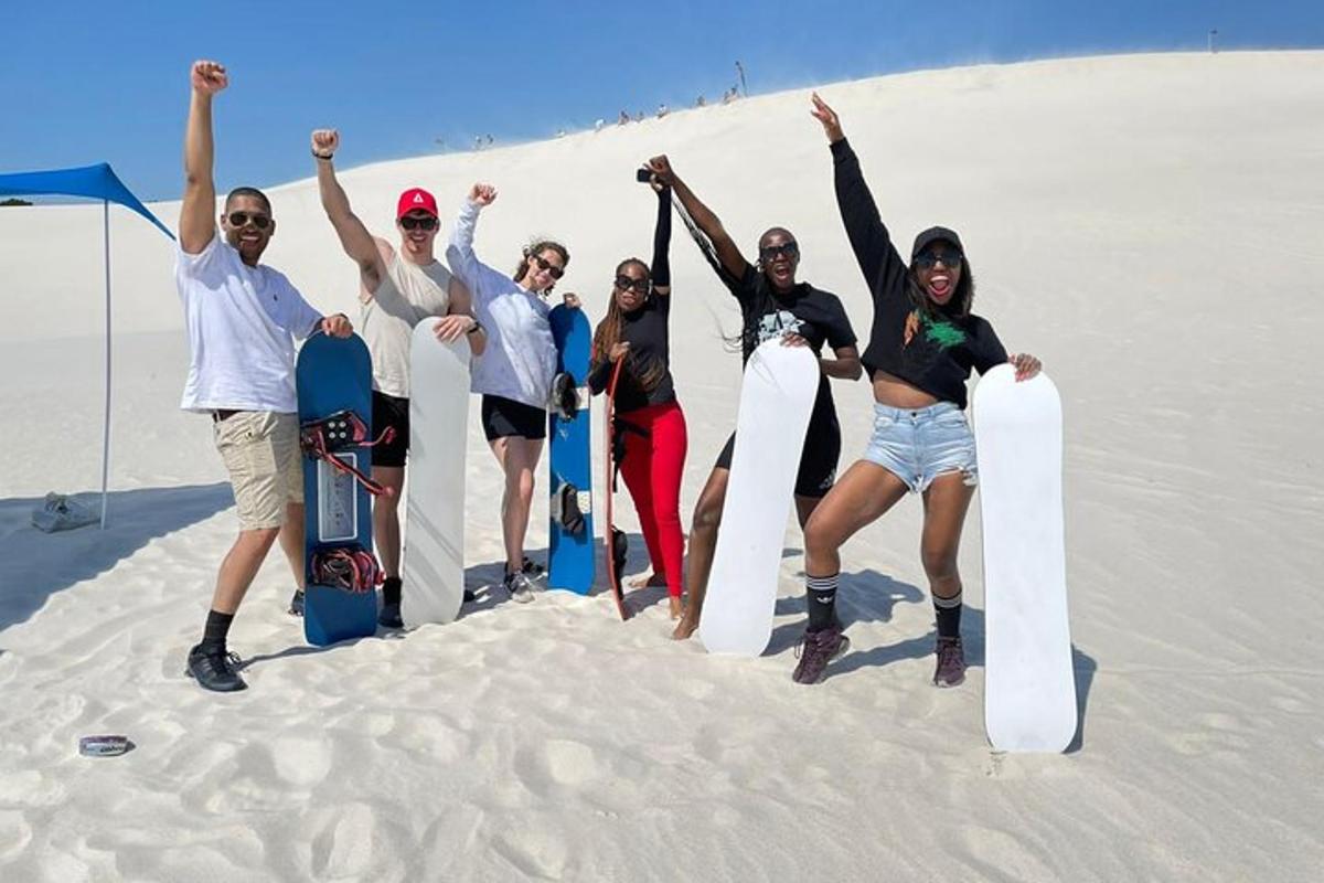 un grup de persones dempeus a la sorra amb les seves taules de snowboard