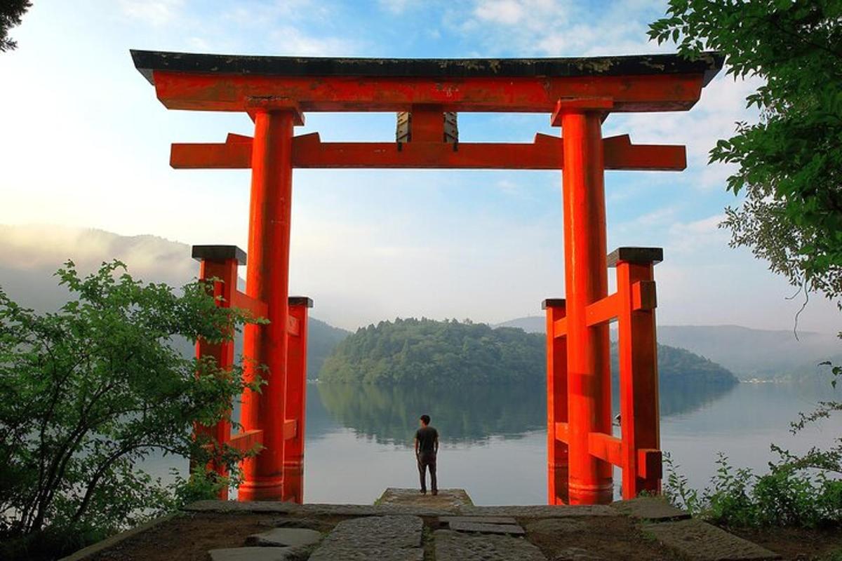un home dret davant d'una porta torii taronja