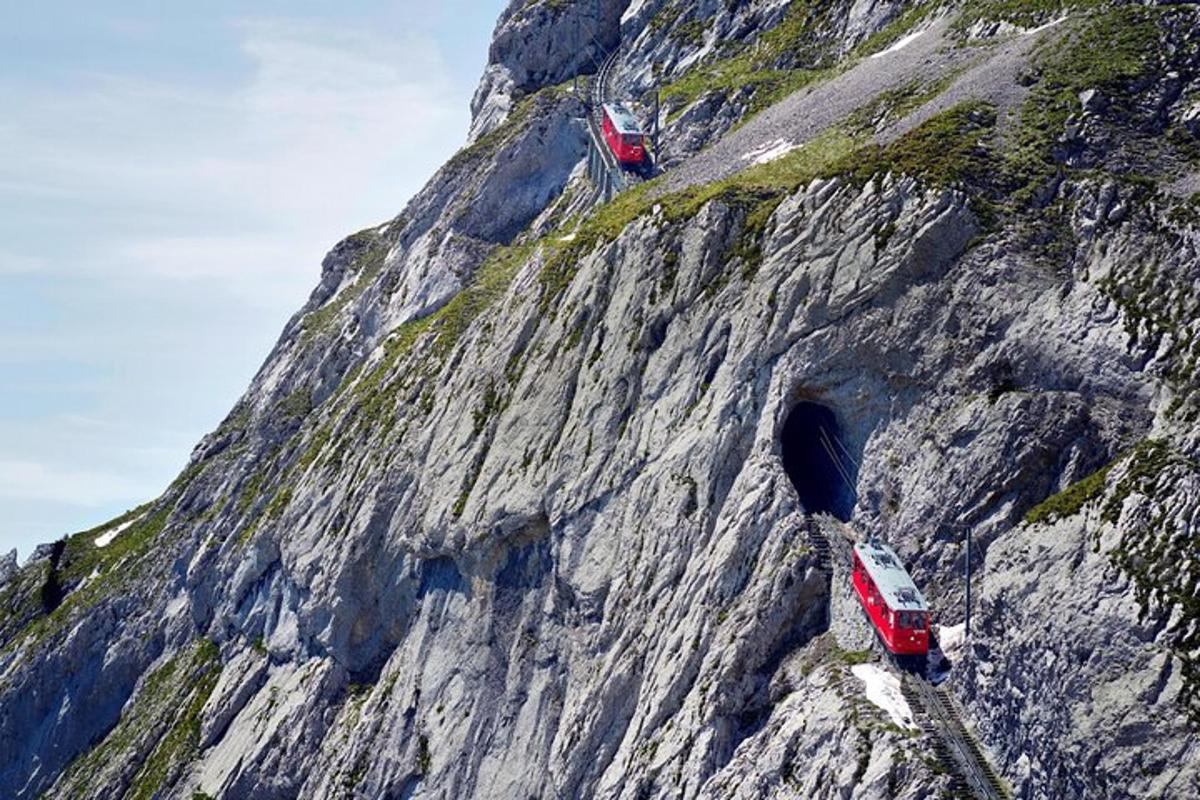 due treni rossi su una montagna rocciosa con un tunnel