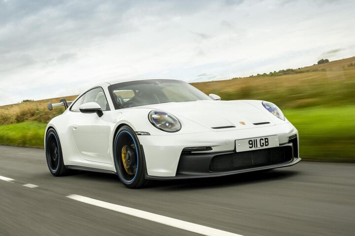un Porsche blanc conduint per una carretera