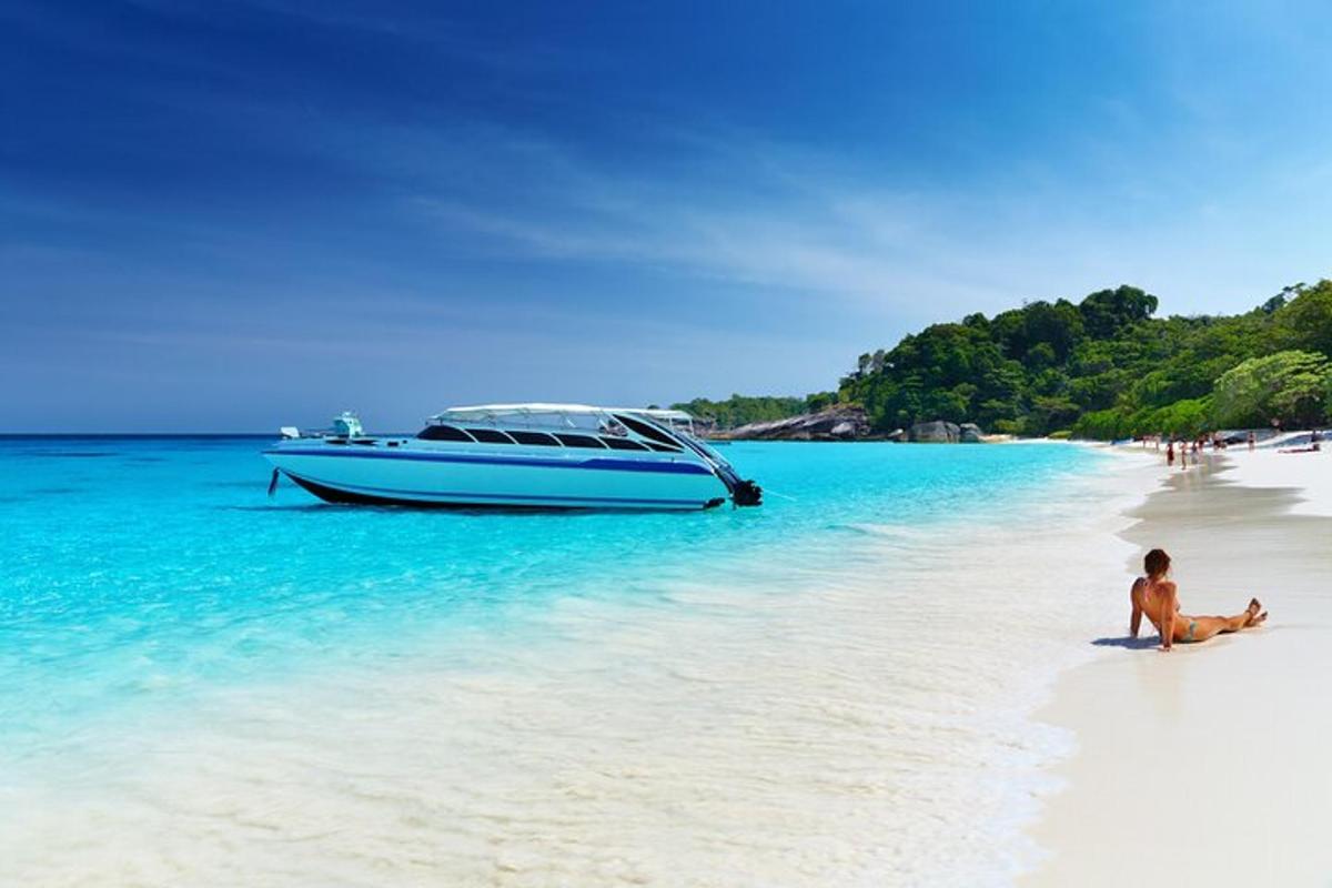 moški, ki sedi na plaži poleg čolna