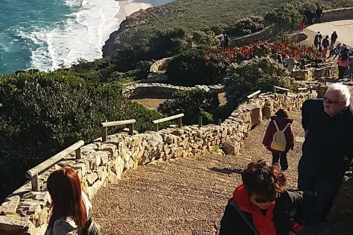 un gruppo di persone che camminano lungo un sentiero di pietra vicino all'oceano