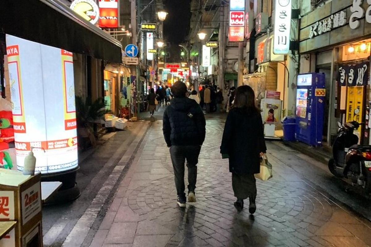 due persone che camminano lungo una strada cittadina di notte