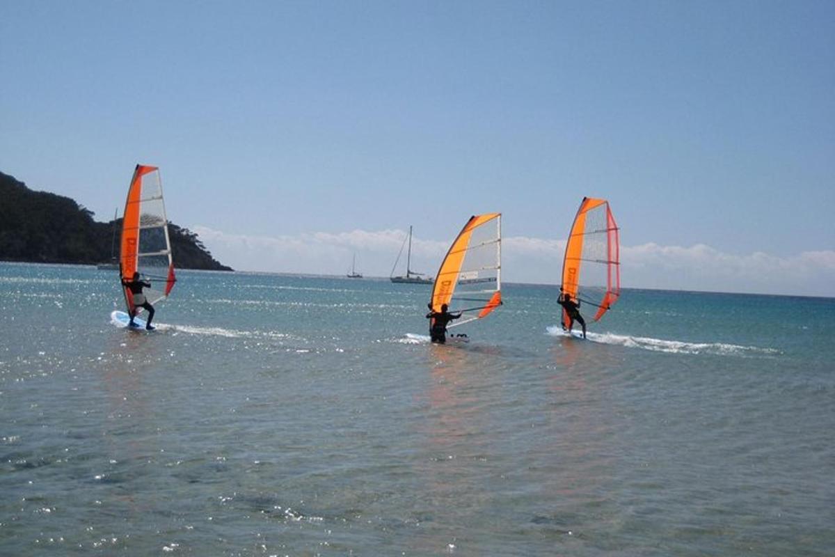 tři lidé surfují na vodě