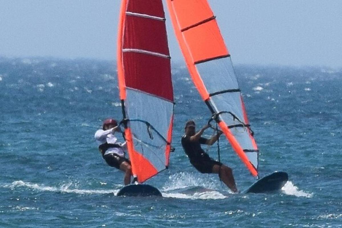 dva lidé windsurfují v oceánu na vodě