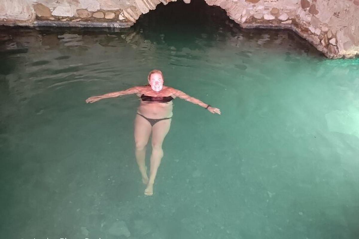 žena plavající ve vodě poblíž jeskyně