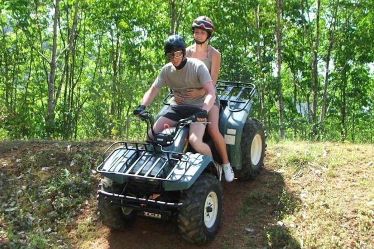 Dos personas viajando en un vehículo de cuatro ruedas por un sendero
