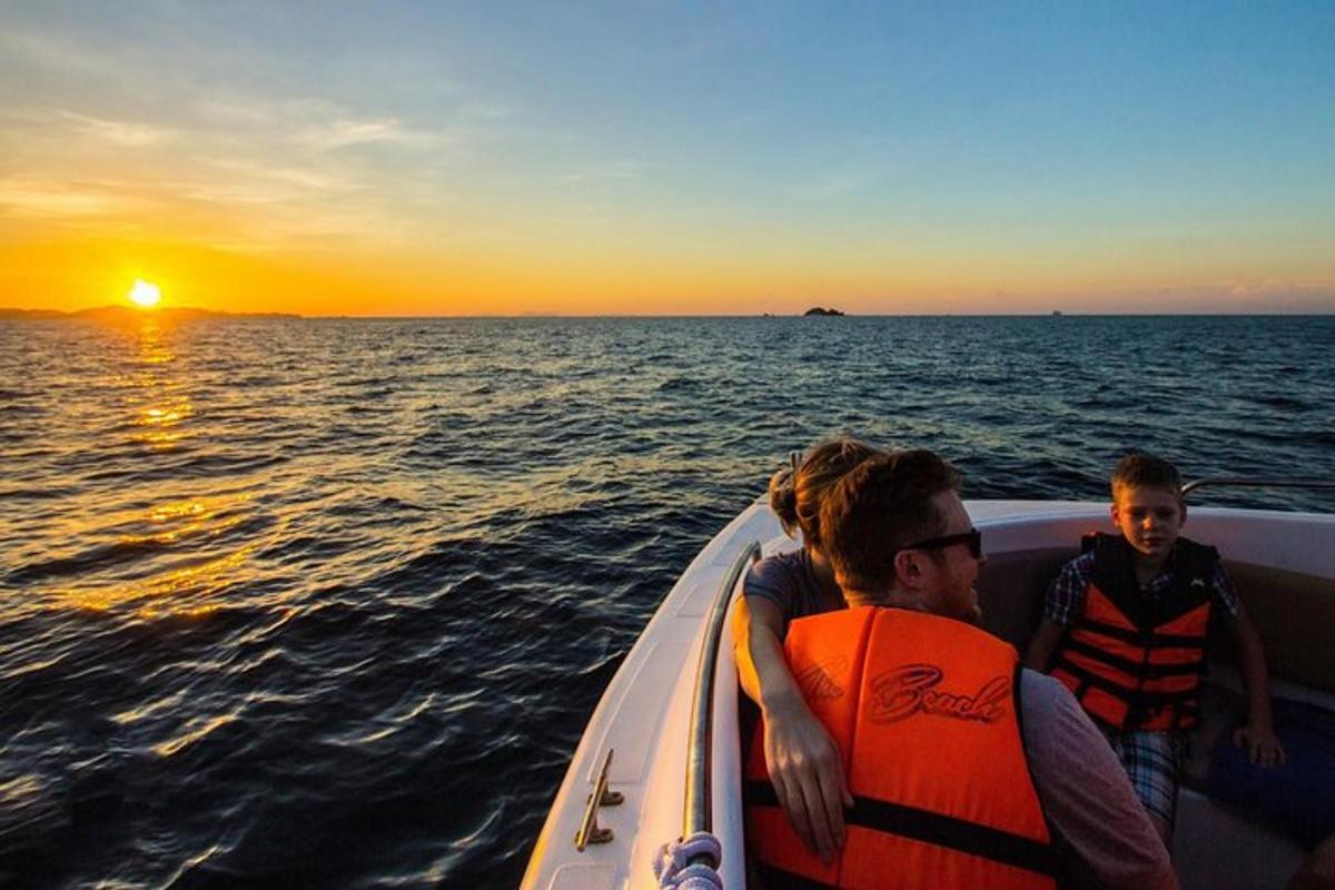 un homme et deux enfants sur un bateau au coucher du soleil