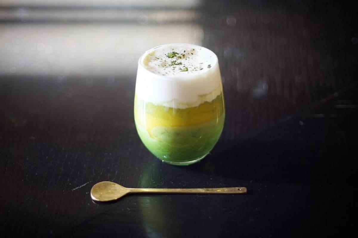 a drink in a glass on a table with a spoon