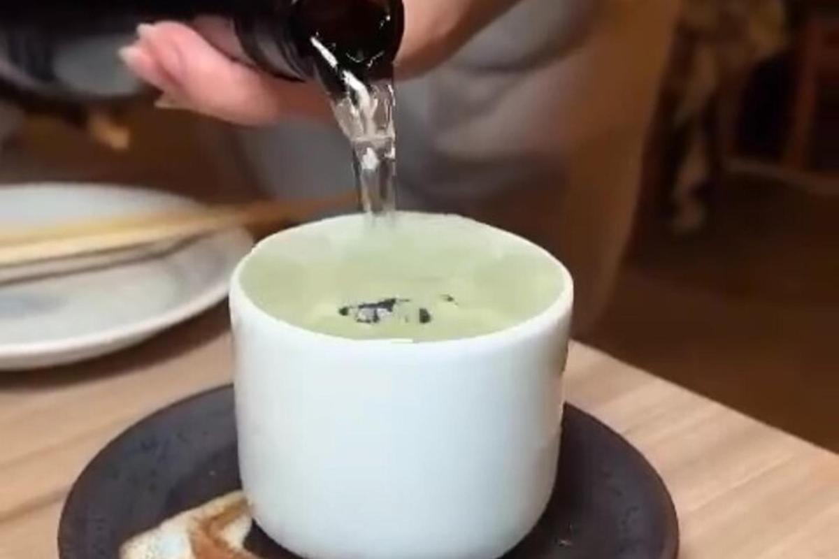 Una persona está vertiendo líquido en una taza blanca.