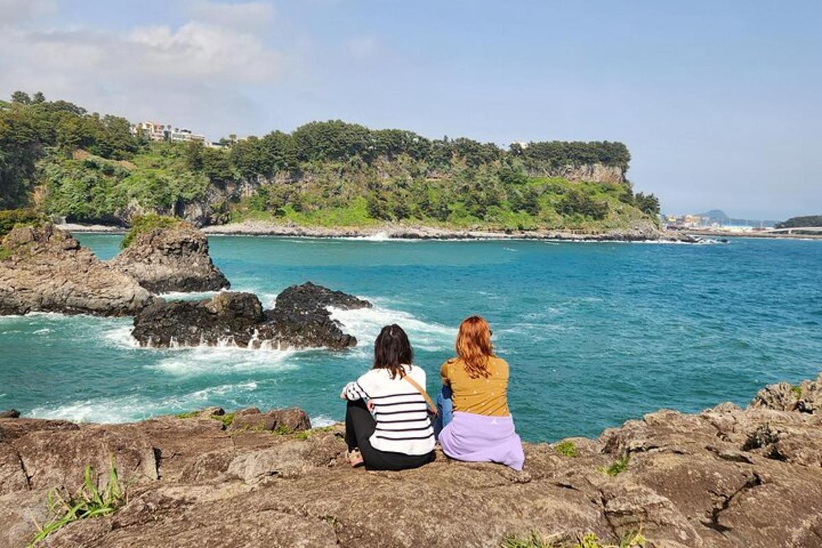 zwei Frauen sitzen auf Felsen und schauen auf das Meer