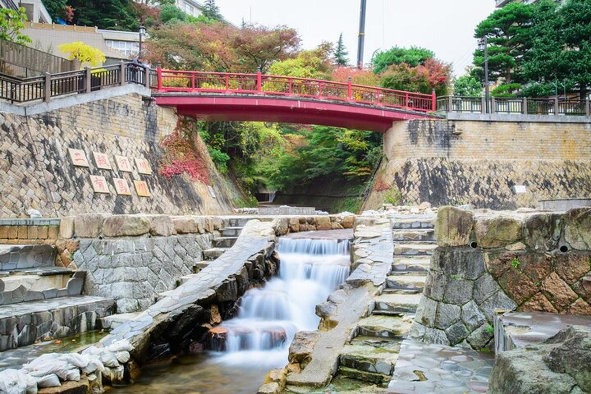 un pont vermell sobre un riu amb cascada
