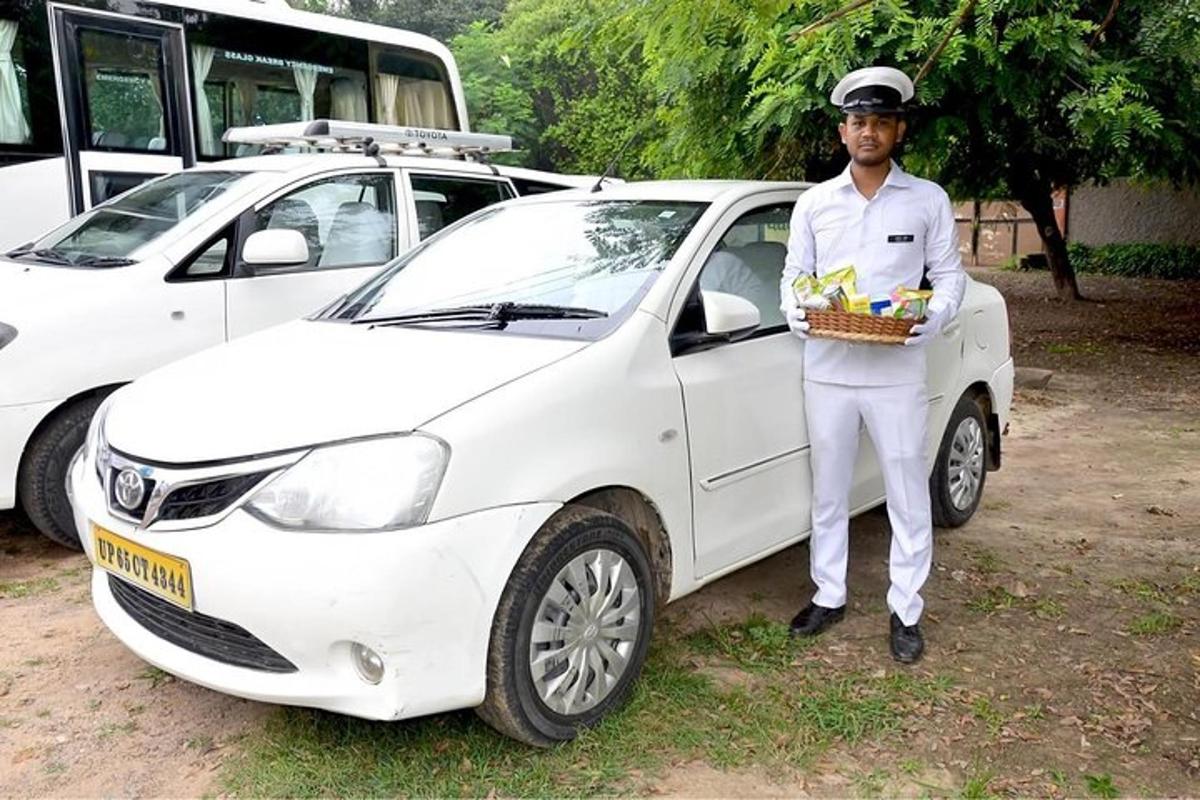 un homme debout à côté d'une voiture blanche avec un panier de fruits
