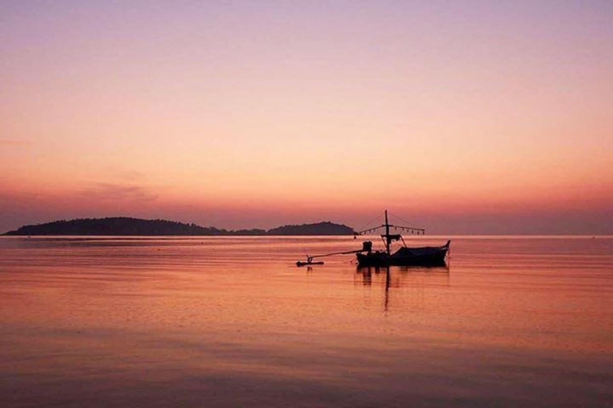 isang bangka na nakaupo sa tubig sa paglubog ng araw