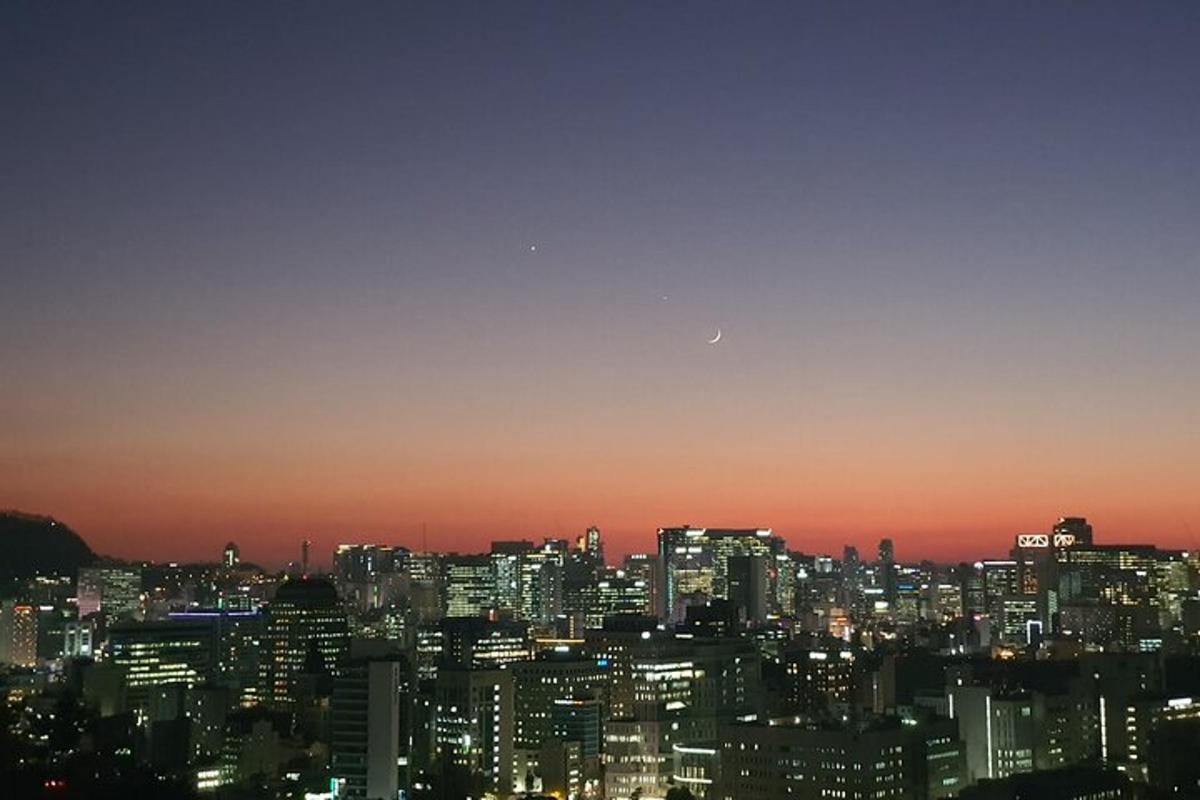 a city skyline at night with the moon in the sky