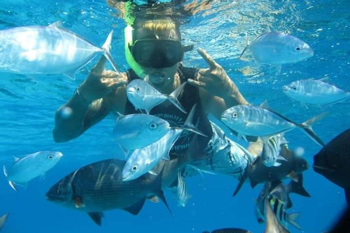 una mujer en el agua con un grupo de peces