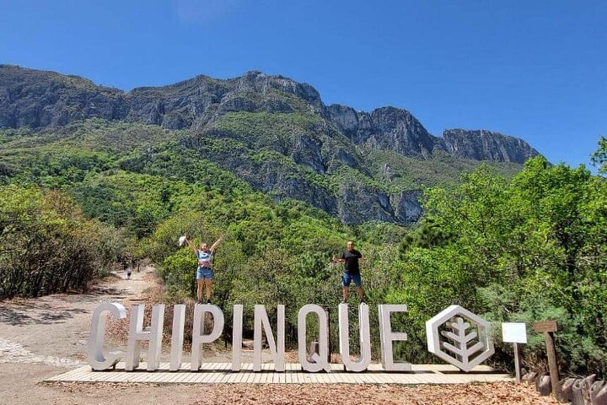 two people standing on top of a sign with mountains in the background