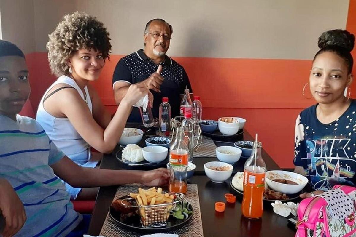 isang grupo ng mga tao na nakaupo sa paligid ng isang mesa na kumakain ng pagkain